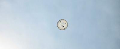 A round parachute seen from below against a clear sky.