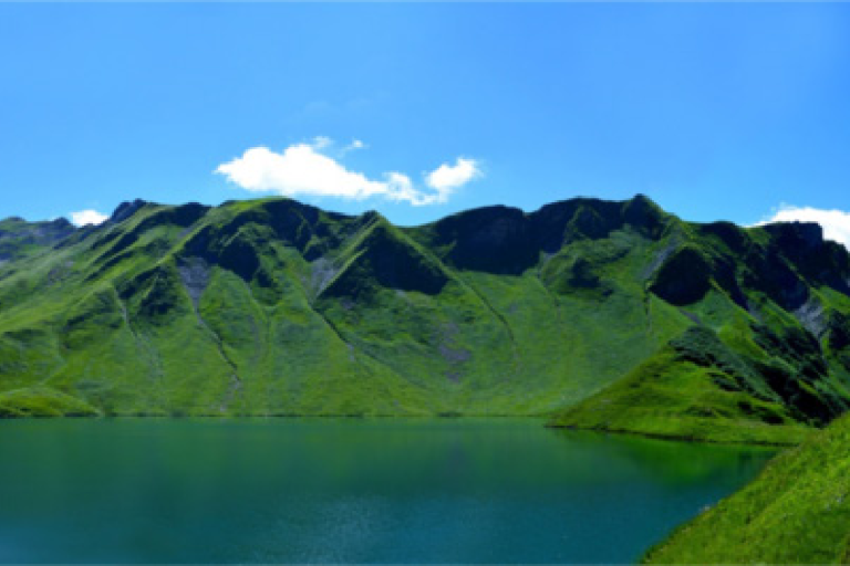 A scenic view of a lake with surrounding mountains and a clear blue sky, featuring a banner about a climate factsheet for lakes from environmental organizations.
