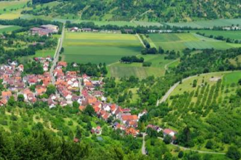 Aerial view of a rural landscape with a village surrounded by forests and fields, next to a banner for the Global Climate Observing System, highlighting a Land Cover factsheet.