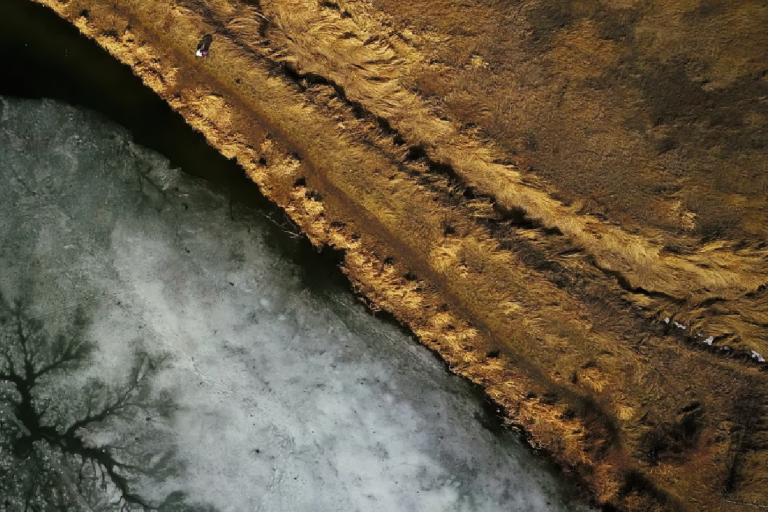 Aerial view of a landscape with a frozen surface on the left and earth on the right. Text on the left reads "Permafrost Essential Climate Variable (ECV) Factsheet" with logos at the bottom.
