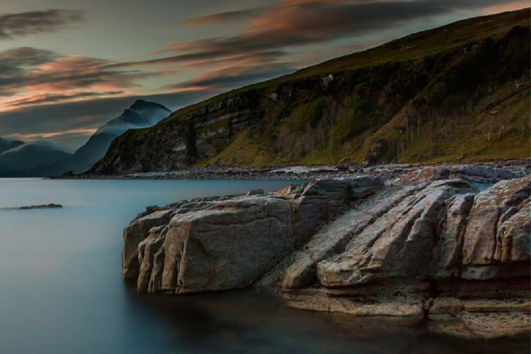 Calm sea bordered by rocky cliffs, with overcast sky. Text overlay: "Sea Level Essential Climate Variable (ECV) Factsheet - Global Climate Observing System.