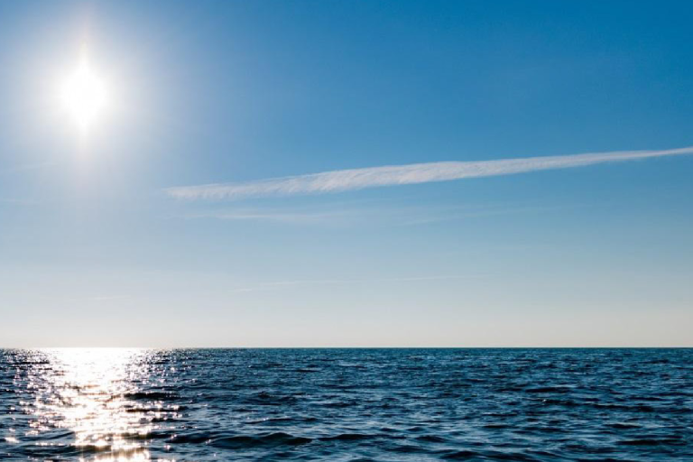 Cover of the Global Climate Observing System factsheet on sea surface temperature, featuring a sunny ocean horizon and logos of WMO, IOC, ISC, and UN Environment.