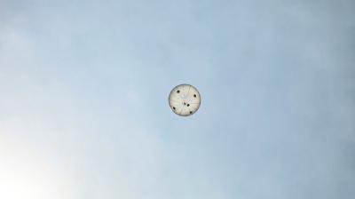 A round parachute seen from below against a clear sky.