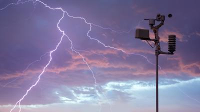 A weather station stands under a stormy sky with multiple lightning bolts visible in the background.